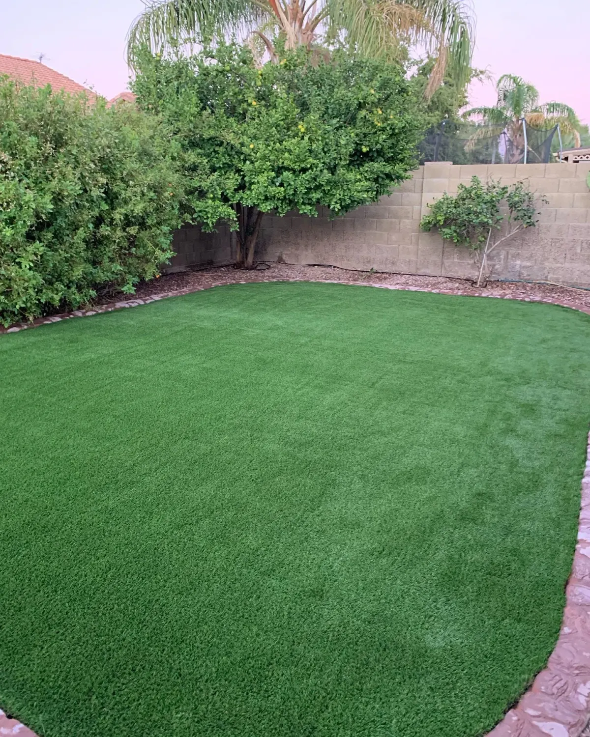 The same yard transformed with vibrant green artificial turf by The Turf Yard